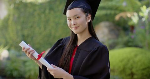 Proud Graduate Beaming in Cap and Gown Holding Diploma