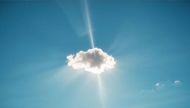 Sunbeam Backlit Cloud in Serene Blue Sky with Flare Effects