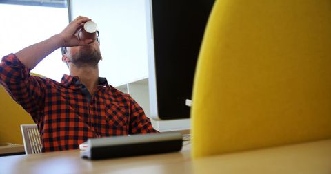 Office break: caucasian man in plaid shirt sipping from cup