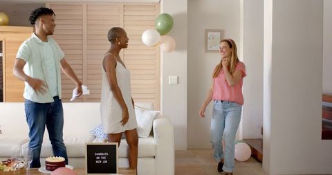Friends Setting Up Living Room Celebration with Balloons