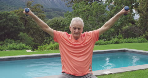 Senior Man Exercising with Dumbbells in Backyard Garden