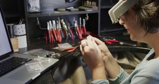 Caucasian female jeweller making jewellery using tools in jewellery shop. Jewellery, enterpreneurship and small business, unaltered.