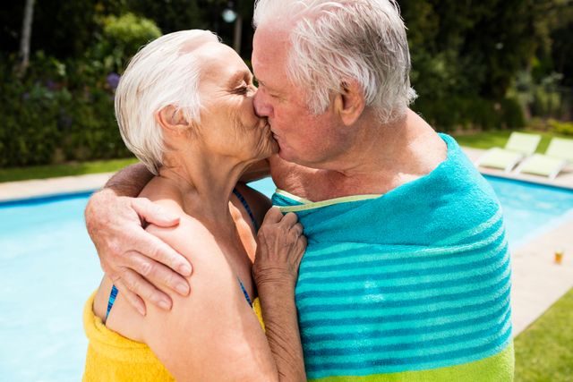 Senior couple kissing each other at poolside on a sunny day