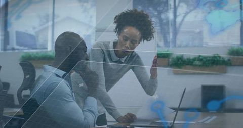 Business colleagues collaborating over laptop and documents with data overlay in office
