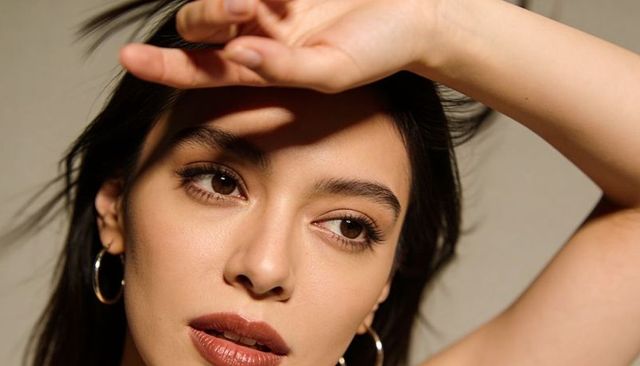 Gazing woman shielding eyes with hand, close-up beauty portrait with warm golden lighting
