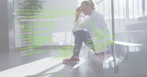 Woman developer sitting on stairs with code overlay, reflecting in bright office atrium