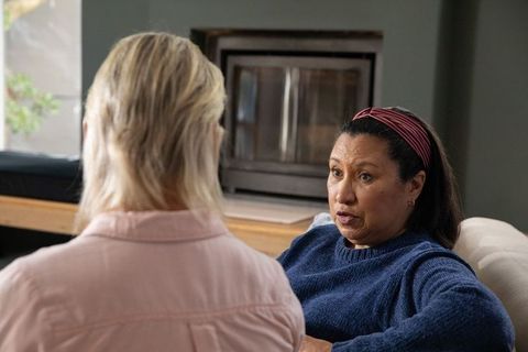 Mature mixed-ethnicity friends having heartfelt conversation on cozy living room couch