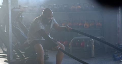 African american man swinging battle ropes during intense gym strength training session