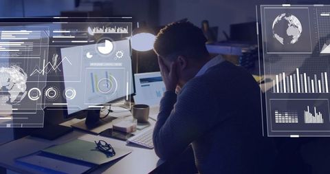 Working late data analyst reviewing multi-screen dashboards and analytics