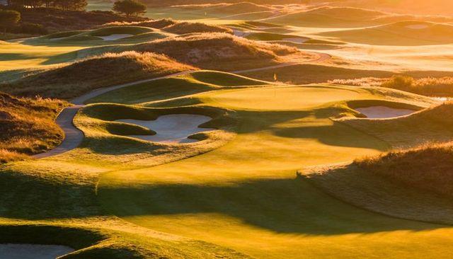 Links golf course basking in golden sunrise light over manicured putting green and bunkers