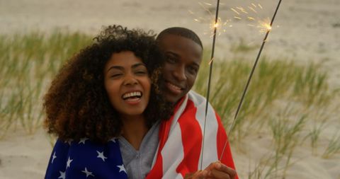 Joyful African American Couple Celebrating with Sparklers at Beach