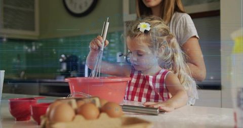Young girl whisking batter on kitchen island while mother supervising home baking
