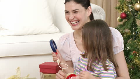 Mother and Daughter Joyfully Unwrapping Christmas Gifts at Home