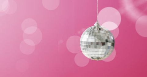 Festive silver disco ball on pink with white light bokeh