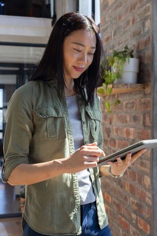 Asian businesswoman engaged with digital tablet in modern industrial office