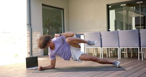 Man Executing Side Plank on Patio with Laptop, Outdoor Wellness