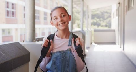Preteen Girl Outdoors Holding Backpack in School Corridor