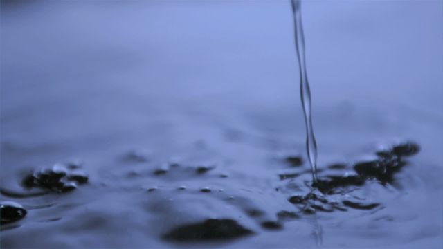 Flowing water moving elegantly under blue light in slow motion captures cinematic beauty. Ripple and droplet interactions convey calmness and depth, great for use in relaxing themes, water-themed publications, or as artistic background.