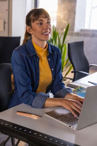 Professional Woman Typing on Laptop at Modern Office Desk