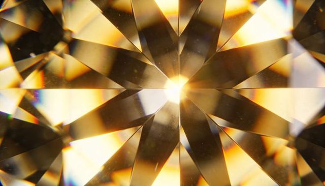 Golden faceted gemstone macro showing star-like brilliance and sparkling prism