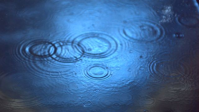 Rain drops falling onto a water surface create beautiful ripples in slow motion. Perfect for conveying themes of tranquility, nature, and relaxation. Ideal for backgrounds, nature-related content, or artistic projects.