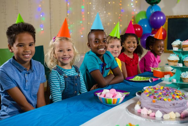 Portrait of smiling children sitting at table during birthday