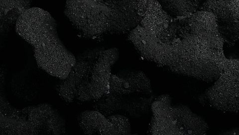 Macro close-up coal texture showing granular porous lumps with mineral flecks in low light