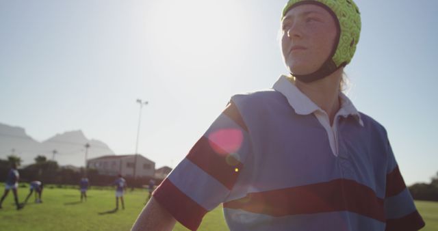 Female Rugby Player in Helmet Standing on Field with Sun Glare - Download Free Stock Images Pikwizard.com