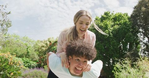 Joyful Couple Enjoying Playful Moment in Lush Garden on Sunny Day