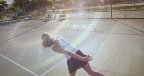 Female Tennis Player Serving Under Golden Hour Sunlight
