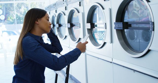 Woman Waiting for Laundry in Self-Service Laundromat while Using Smartphone - Download Free Stock Images Pikwizard.com