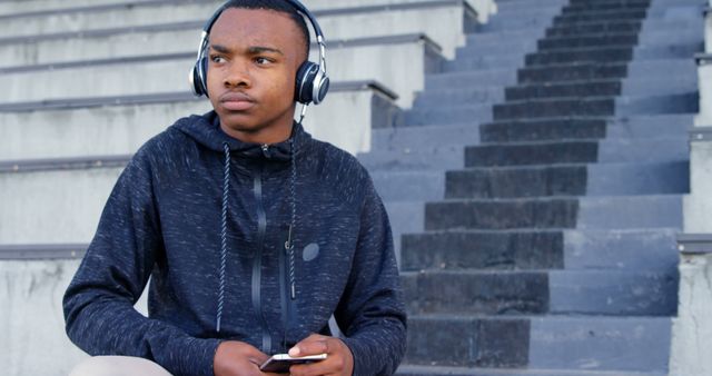 Young Man Listening to Music on Headphones in Outdoor Staircase - Download Free Stock Images Pikwizard.com