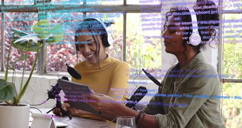 Recording cohosts using tablet and microphones by sunlit window with plants