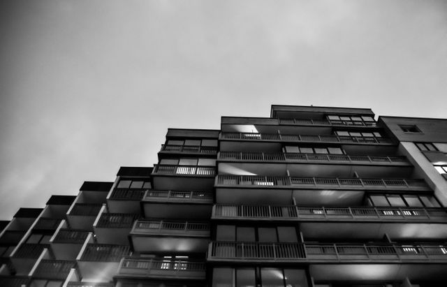 Architectural black and white capture of a high-rise building in an urban setting during dusk. Suitable for cityscape visuals, real estate promotions, architectural studies, or urban lifestyle themes.