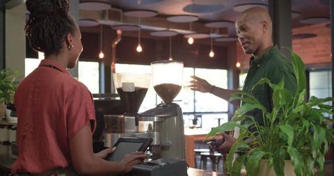 African american barista taking order from smiling customer at modern coffee counter