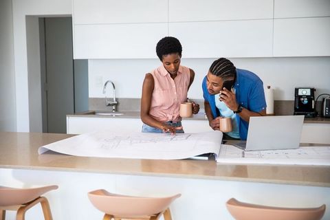 Couple Discussing Home Blueprints in Modern Kitchen Setting