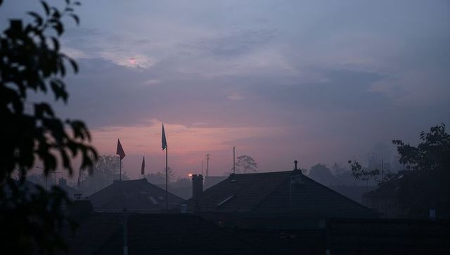 Foggy dawn silhouetted rooftops with flags over quiet suburb skyline
