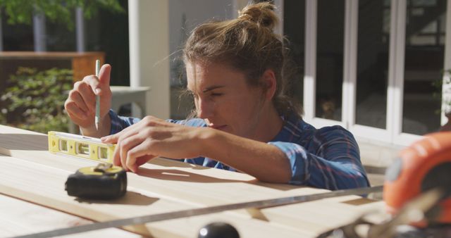 Focused Young Woman Using Level Tool for Woodworking Project Outdoors - Download Free Stock Images Pikwizard.com