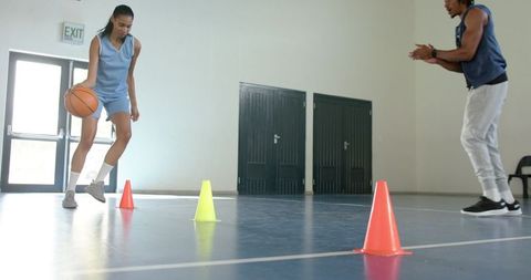Coach and athlete practicing cone dribbling in basketball training