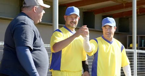 Sunlit community baseball teammates celebrating handshake at dugout entrance