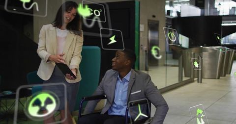 Inclusive business collaboration presenting tablet to wheelchair user in modern glass lobby