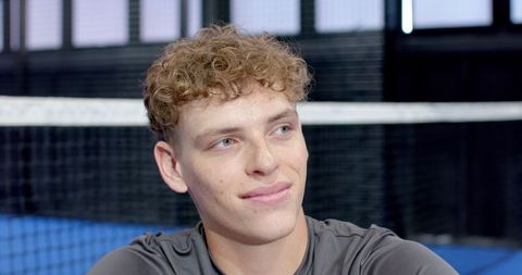 Athletic Man Relaxing Courtside on Indoor Tennis Court
