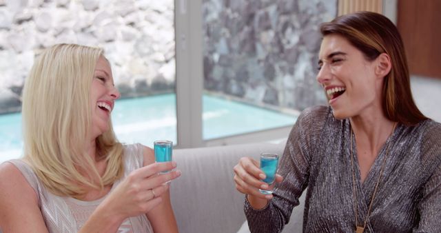 Happy women drinking shots on the sofa