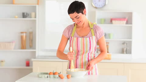 Smiling Woman Baking in Modern Kitchen with Eggs