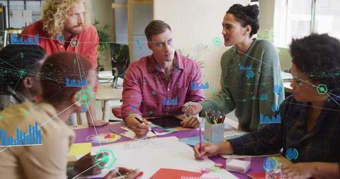 Collaborating team analyzing data and sketching business strategy around tablet in modern office