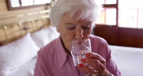 Senior Woman Drinking Water While Taking Medication