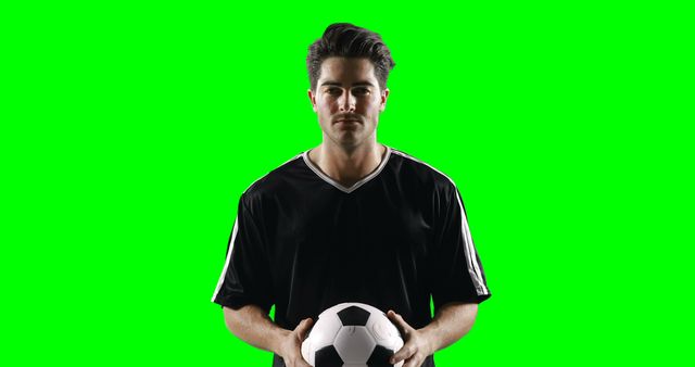 This image features a soccer player in uniform holding a soccer ball against a green screen backdrop. Ideal for sports promotions, advertising, or any project requiring isolation for custom backgrounds or effects.