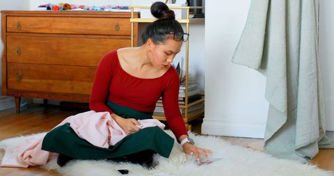 Fashion designer engaging with fabric materials at studio, showcasing artistic process. Ideal for use in promotions related to fashion design, creative industries, and artistic inspiration. Highlights professional working environment and design innovation.