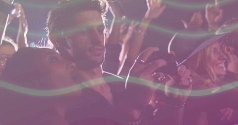 Couple recording live concert on smartphone amid neon stage lights and crowd energy