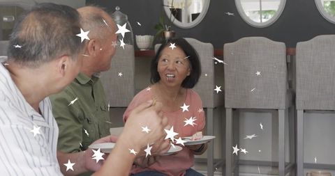 Senior woman sharing dessert and chatting with friends at kitchen island with star confetti